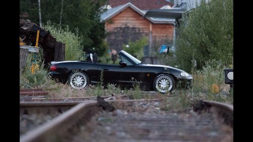 Vintage car on road amidst trees and buildings