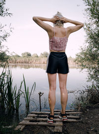 Rear view of woman standing by lake