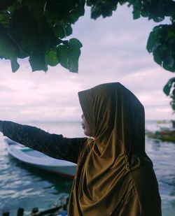 Rear view of woman on shore against sky