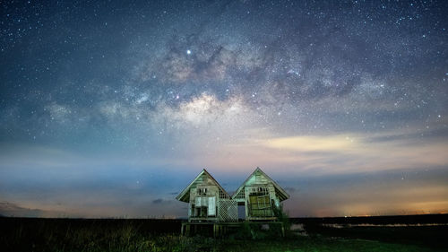 Low angle view of abandoned huts against star field in sky at night