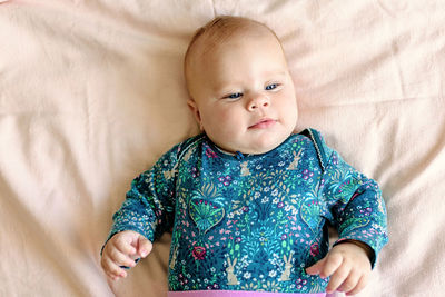 Smiling three month old baby in pink pants on a diaper. top view.