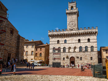 Group of people in front of building against clear blue sky