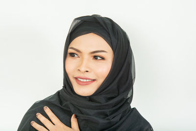 Portrait of smiling young woman against white background