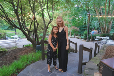 Portrait of young woman with girl in park