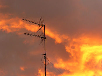 Low angle view of silhouette electricity pylon against dramatic sky