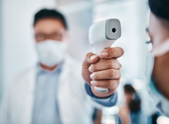 Midsection of scientist holding thermometer