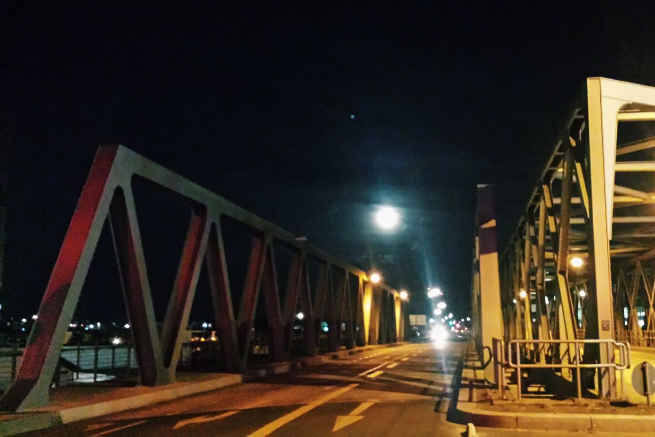 illuminated, night, built structure, architecture, the way forward, transportation, diminishing perspective, railing, sky, lighting equipment, bridge - man made structure, street light, empty, vanishing point, in a row, connection, building exterior, outdoors, no people, copy space