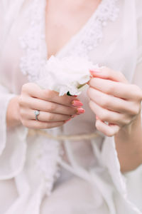 Midsection of bride holding white flower