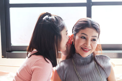 Young woman whispering to mother at home