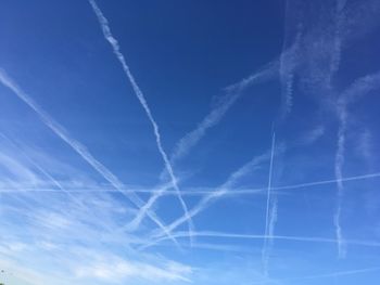 Low angle view of vapor trails against blue sky