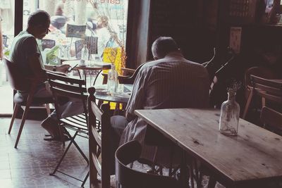 Rear view of people sitting on bench in restaurant