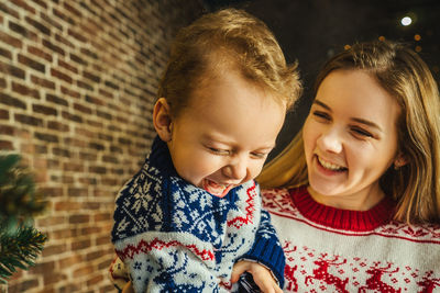 Happy mother and son against wall