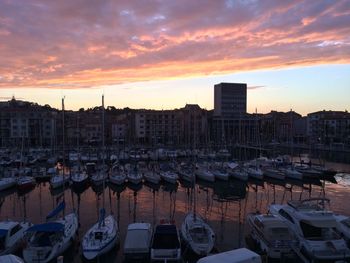 Boats at harbor against cloudy sky