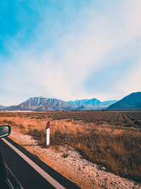 Scenic view of field by mountains against sky