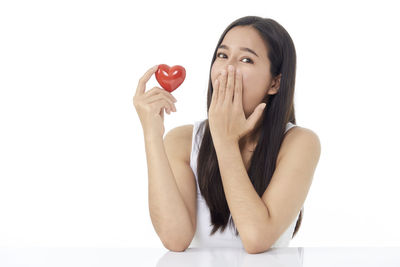 Portrait of young woman holding apple against white background