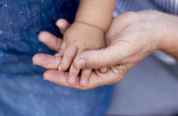 Close-up of grandparent holding baby hands