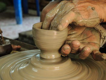 Cropped hands making pot on pottery wheel