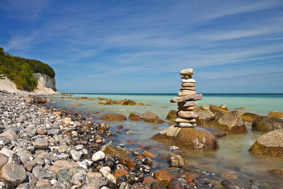 Stack of stones on rock against blue sky