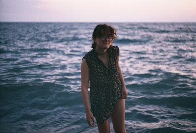 Portrait of young woman standing on shore at beach