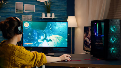 Rear view of girl playing video game at home