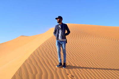 Full length of man standing on desert against clear sky