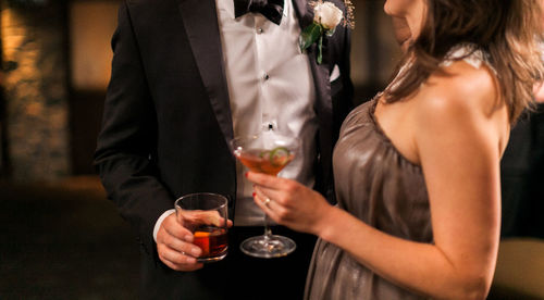 Midsection of friends drinking glass