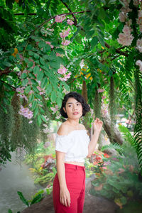 Portrait of woman standing against trees