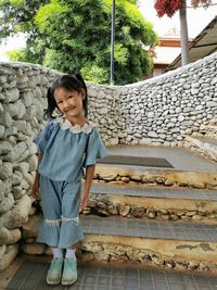 Portrait of smiling girl standing against staircase