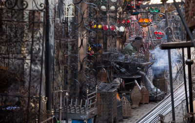 Vendor sitting amidst antique metal decorations at market