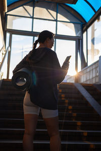 Rear view of young woman standing on escalator