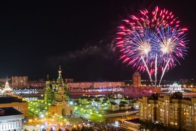 Firework display over illuminated buildings in city at night