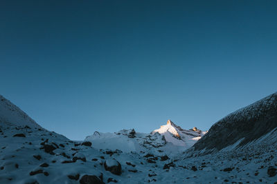 Scenic view of snowcapped mountains against clear blue sky