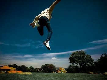 Low angle view of man jumping against sky