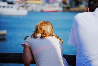 Rear view of man and woman standing by railing against river