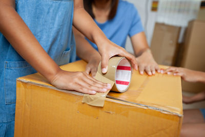 Midsection of girl packing cardboard box at home
