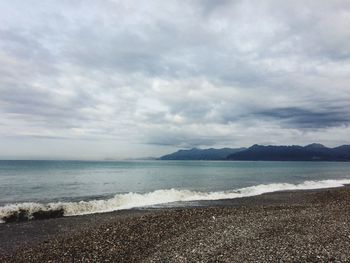 Scenic view of beach against cloudy sky