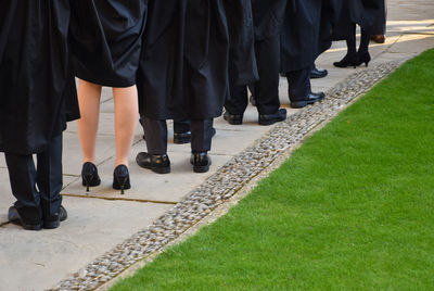 Low section of students standing by grassy field in university