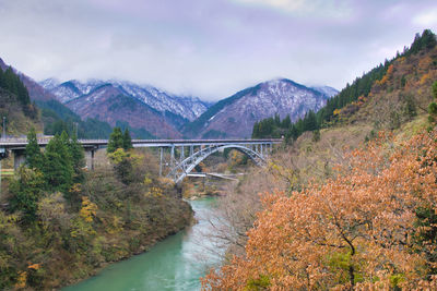 Bridge over river amidst mountains against sky