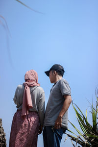 Low angle view of couple standing against clear sky