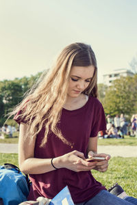 Female high school student text messaging on mobile phone at schoolyard