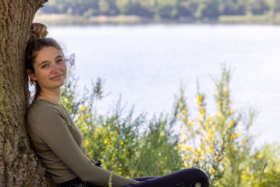 Portrait of young woman looking away against lake