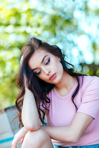 Thoughtful beautiful woman with hand in hair sitting outdoors