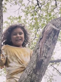 Portrait of smiling girl on tree trunk