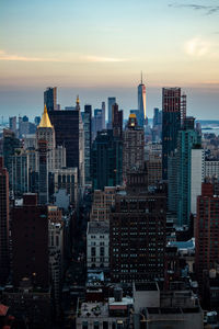 Modern buildings in city against sky during sunset