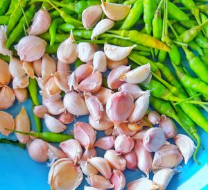 Directly above shot of garlic cloves with green chili peppers in bowl