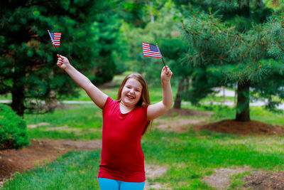 Cute overweight girl with small american flags standing at public park