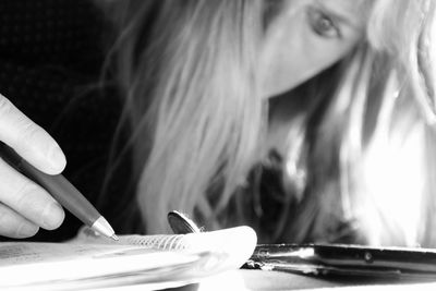 Close-up of woman writing in book