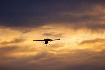 Low angle view of silhouette airplane against sky during sunset