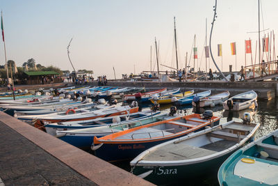 Boats moored at harbor against clear sky