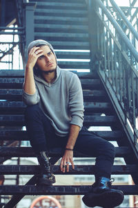 Young man looking away while sitting on staircase